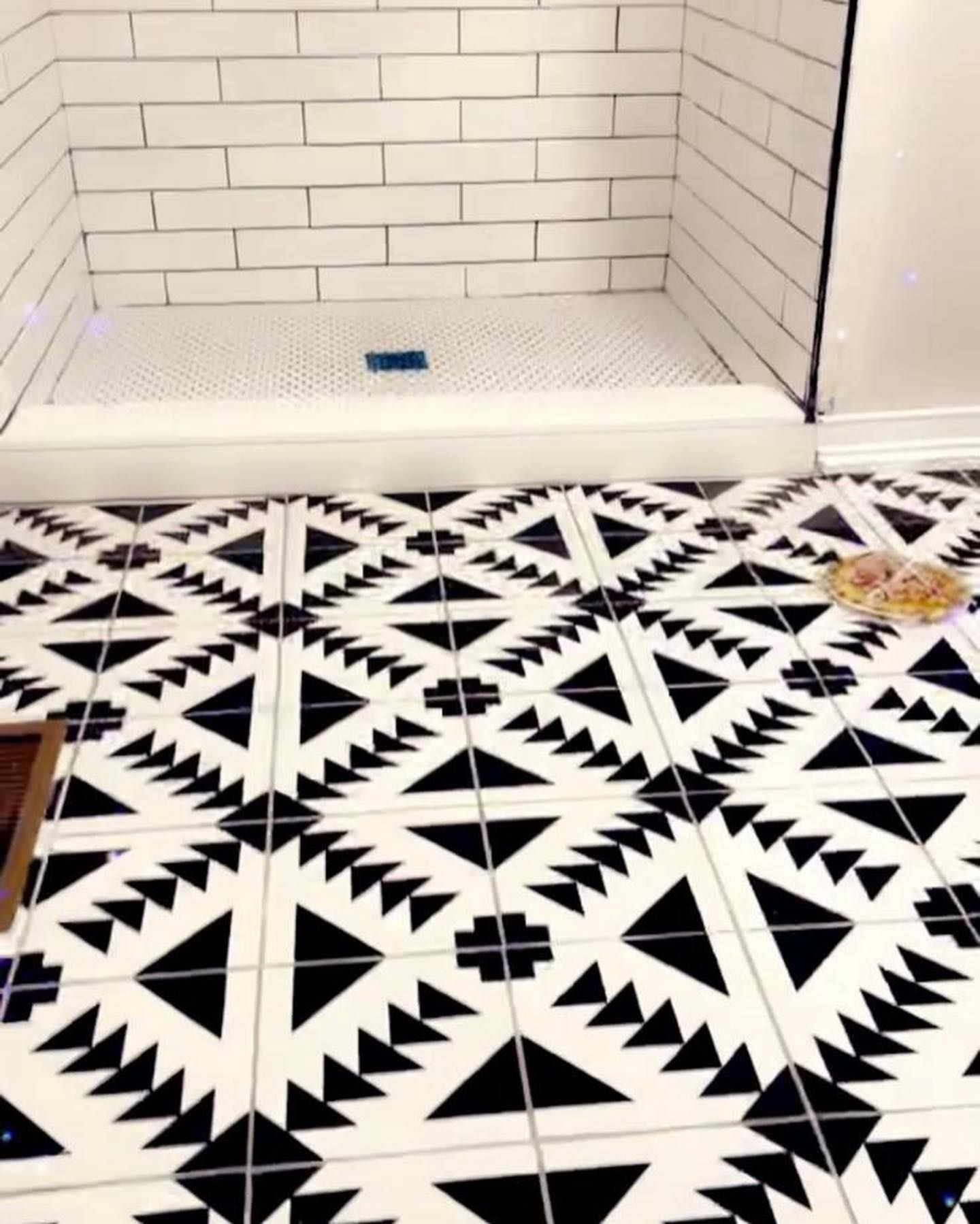 Bathroom with black and white patterned floor tiles, white subway tile shower surround.