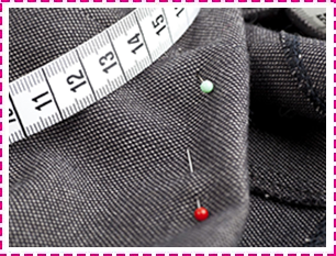 A measuring tape is pinned to a piece of fabric