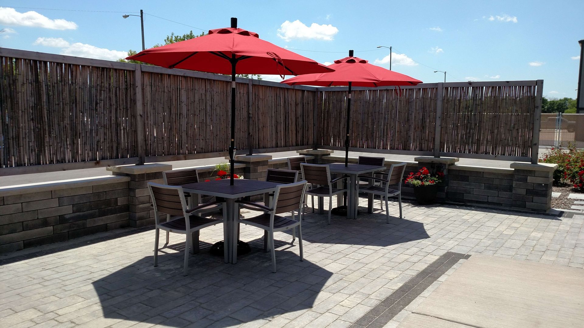 A patio with tables and chairs and red umbrellas.