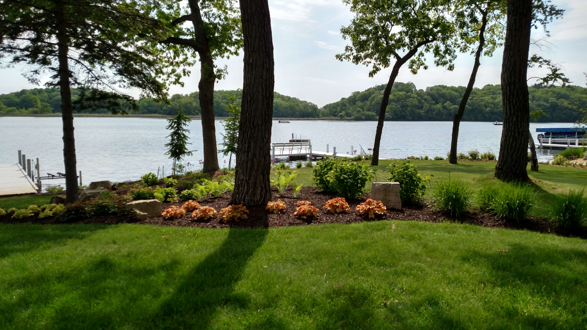 A view of a lake through the trees with a boat docked in the distance.