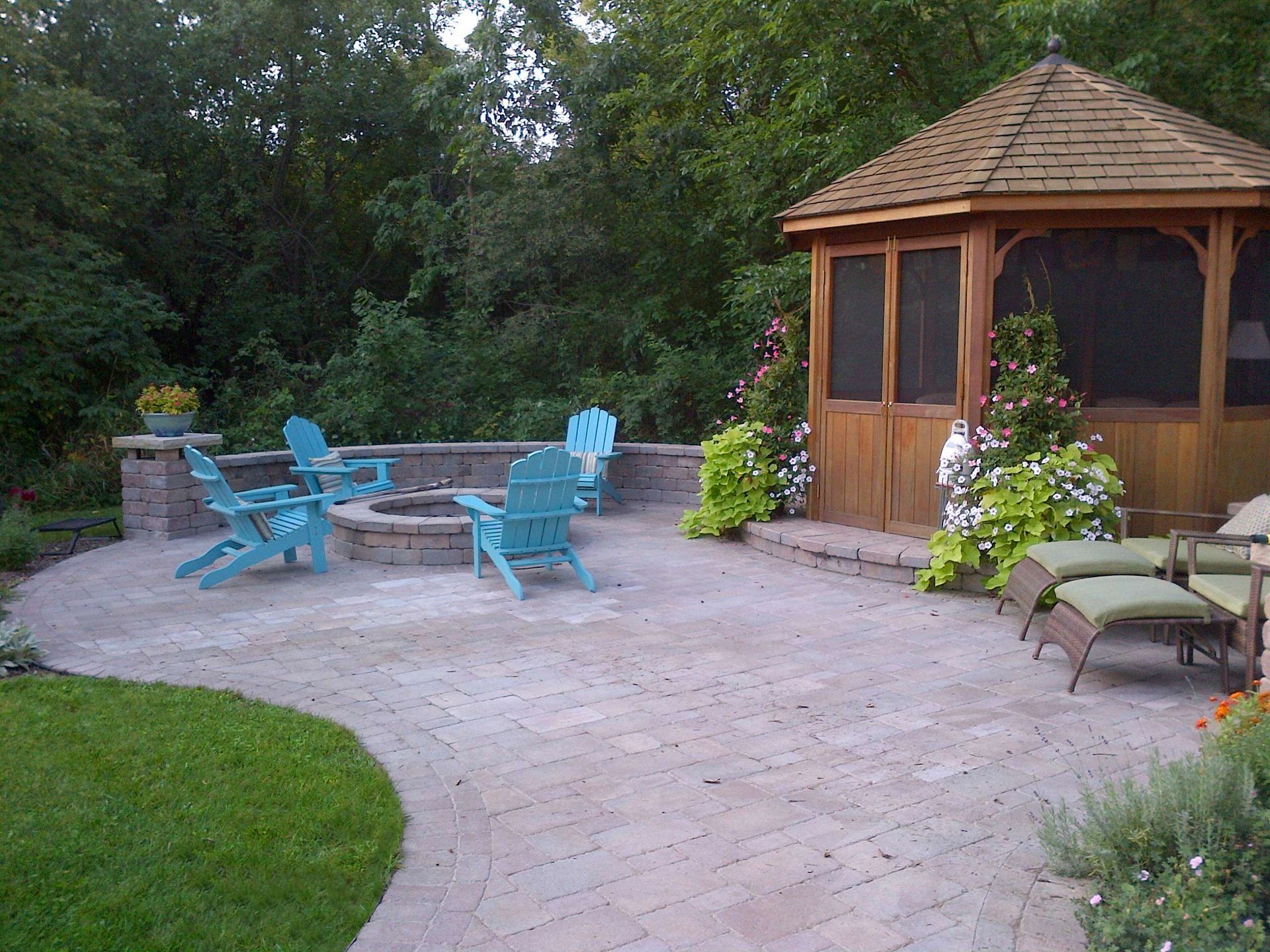 A patio with blue chairs and a gazebo in the background.
