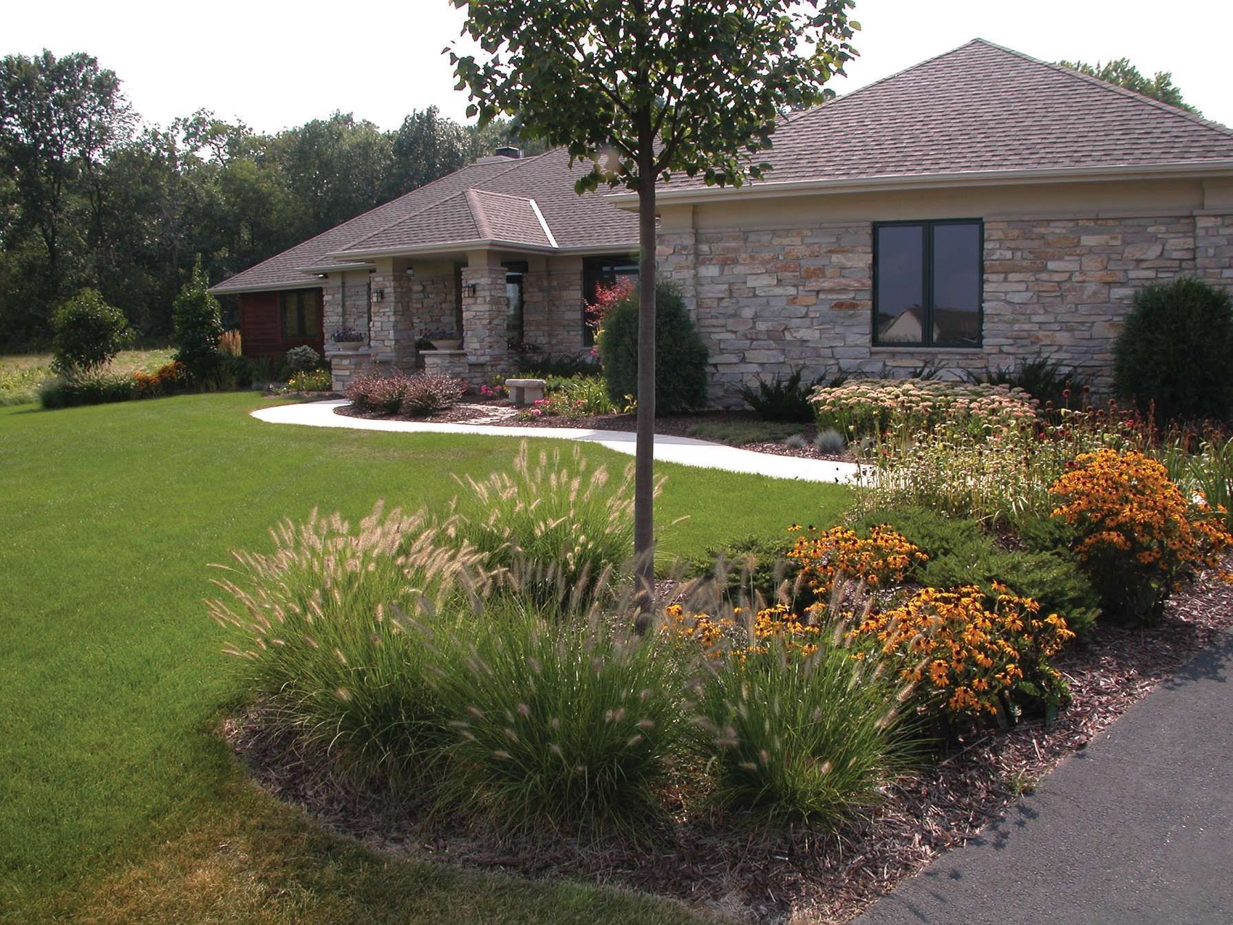 A house with a lush green lawn and flowers in front of it