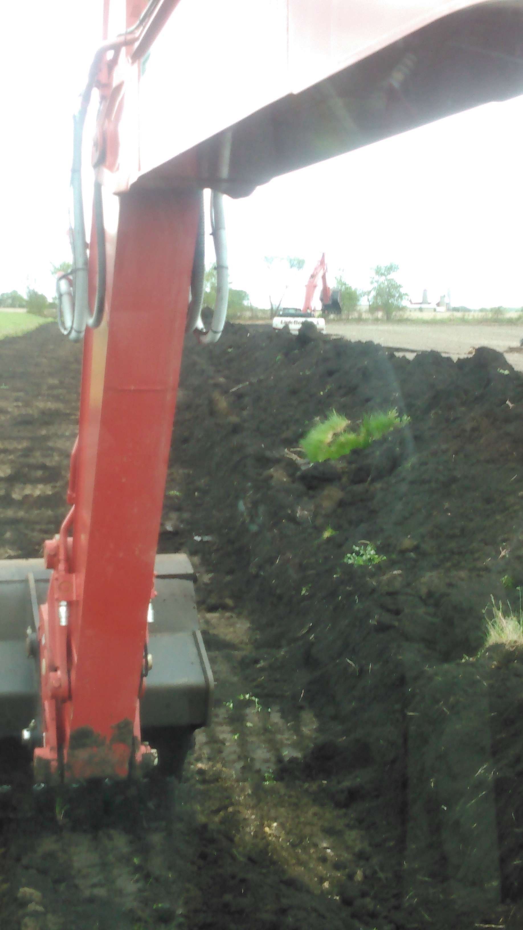 A red excavator is digging in a pile of dirt