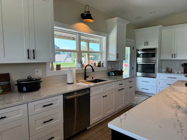 White kitchen with stainless steel appliances, dark hardware, and light countertops.