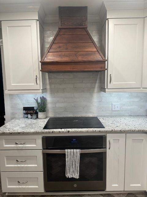 Kitchen with white cabinets, copper range hood, and black oven.