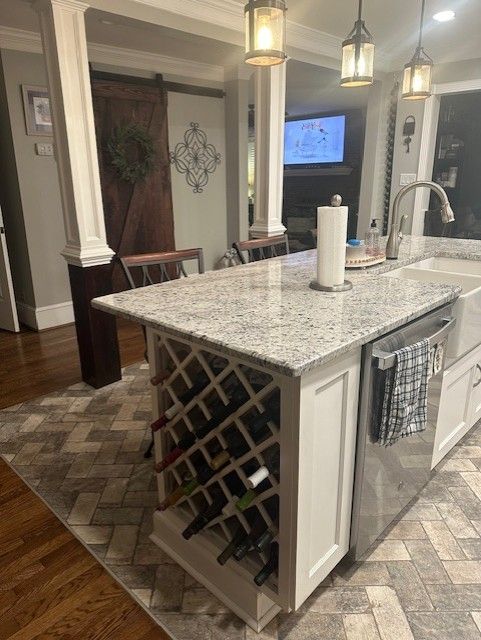 Kitchen island with wine rack, granite countertop, farmhouse sink, and herringbone rug.