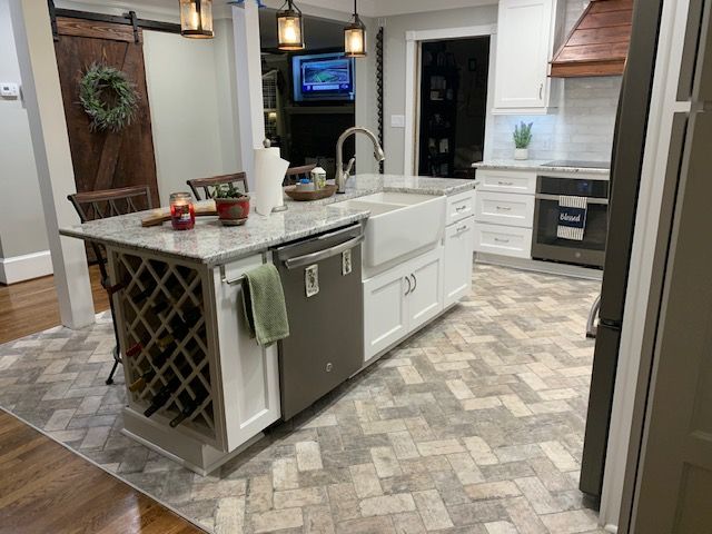 Kitchen with a white island, brick-patterned floor, and wooden barn door.