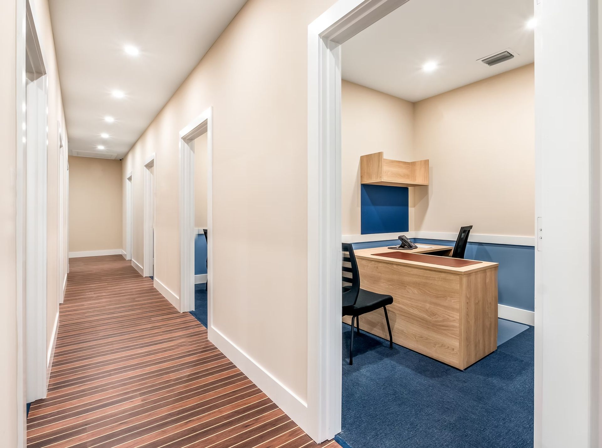 Office hallway with carpeted corridor and open reception desk on blue carpet