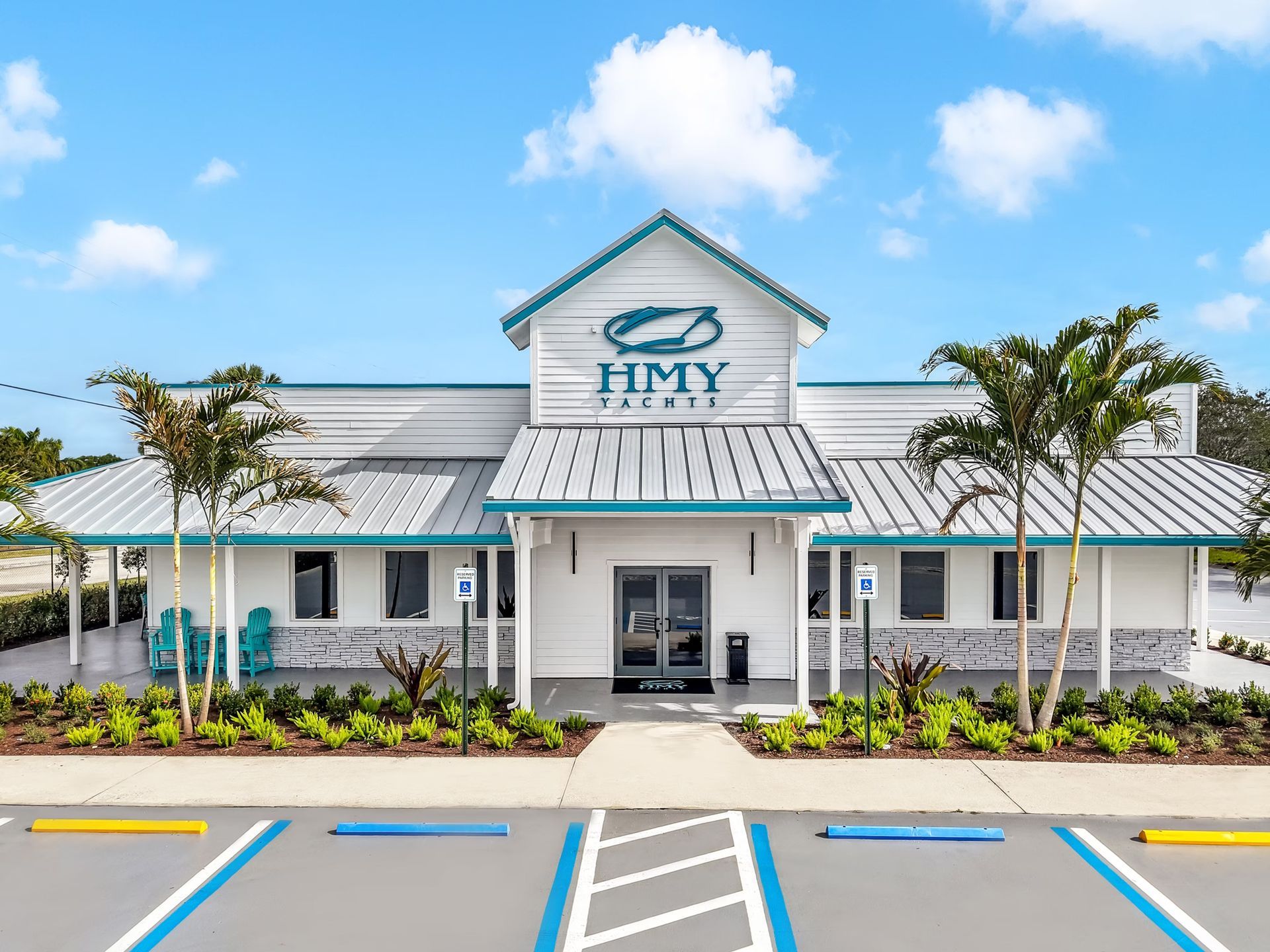 White coastal-style building with blue roof and palm trees under a bright sky