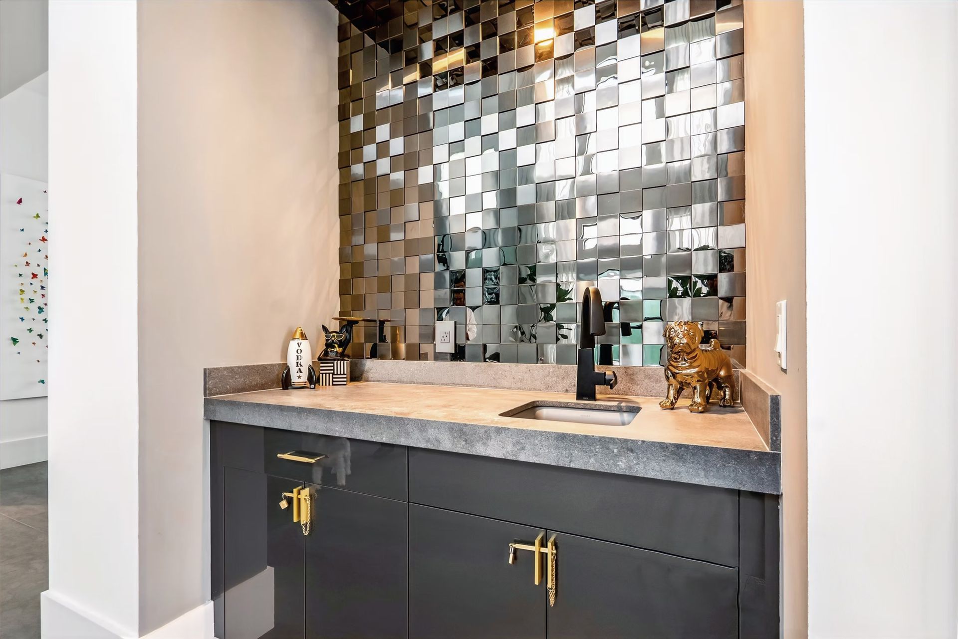 Modern bathroom vanity with dark cabinets, stone countertop, and metallic mosaic backsplash