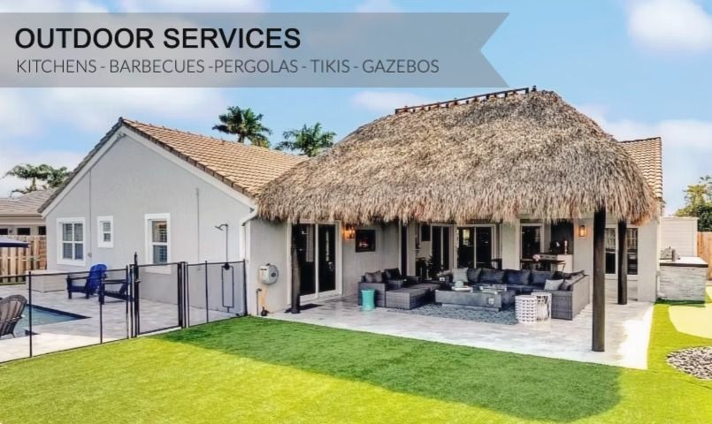 Outdoor services patio with thatched gazebo, gray house, and green lawn under a blue sky