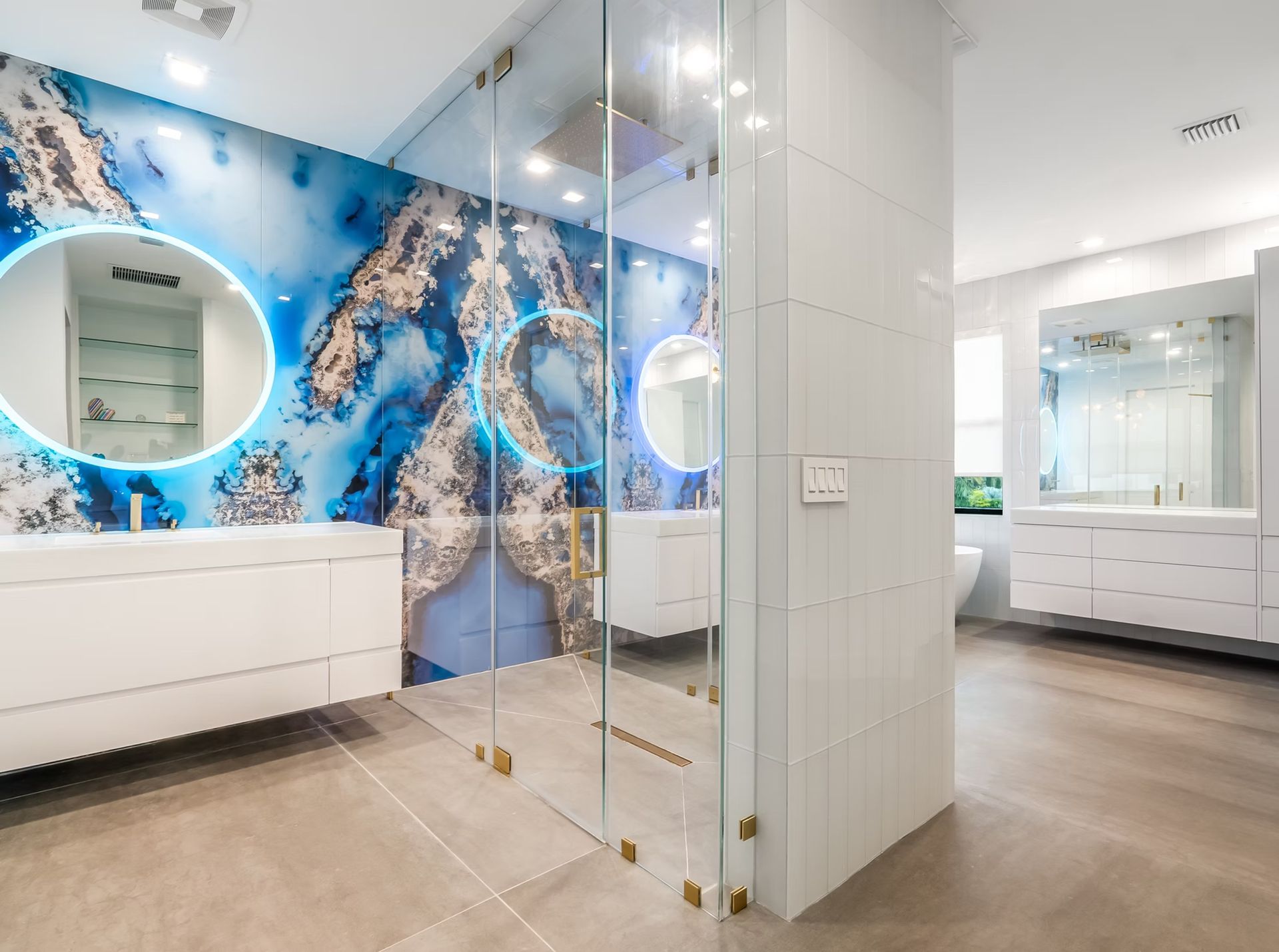 Modern bathroom with blue ocean mural, white vanity, glass shower, and light wood floor