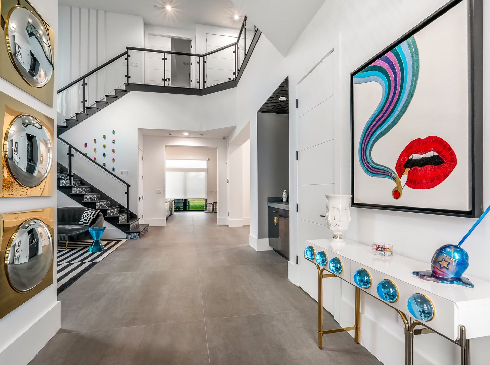 Modern white foyer with staircase, bold wall art, and colorful console decor