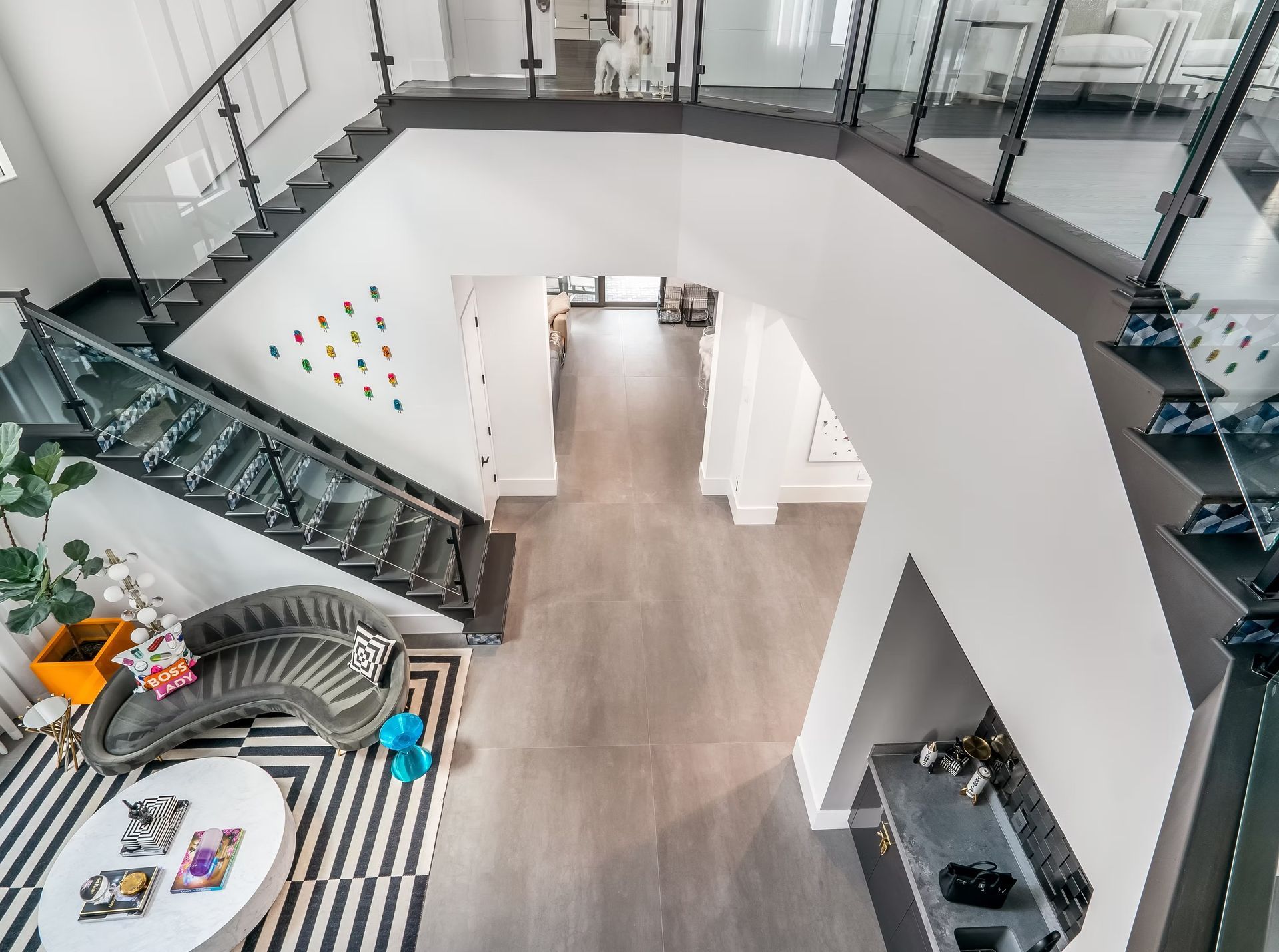 Modern home atrium with curved staircase, glass railings, and bright open foyer