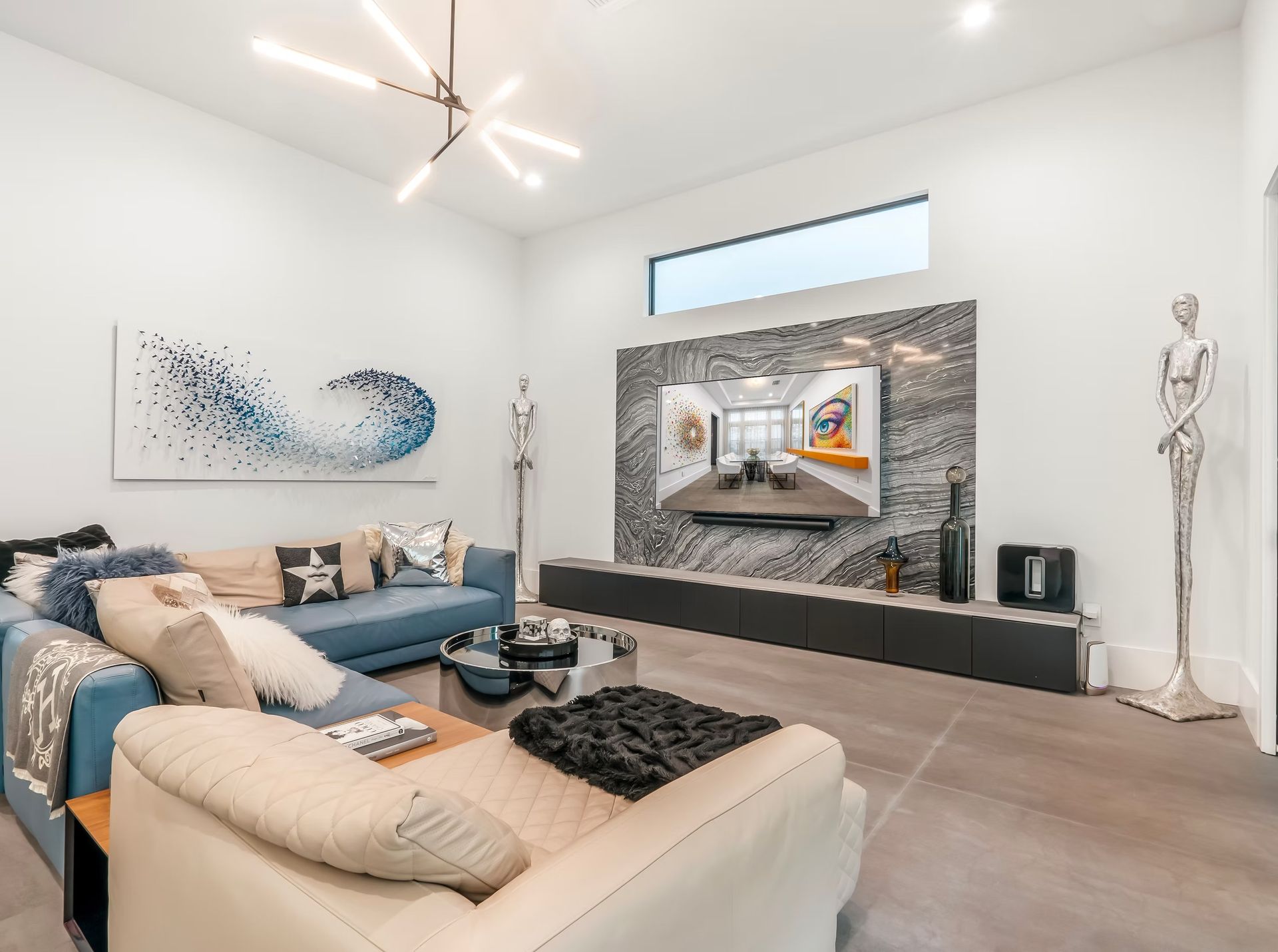 Modern living room with blue sectional sofa, wall art, large TV, and contemporary decor