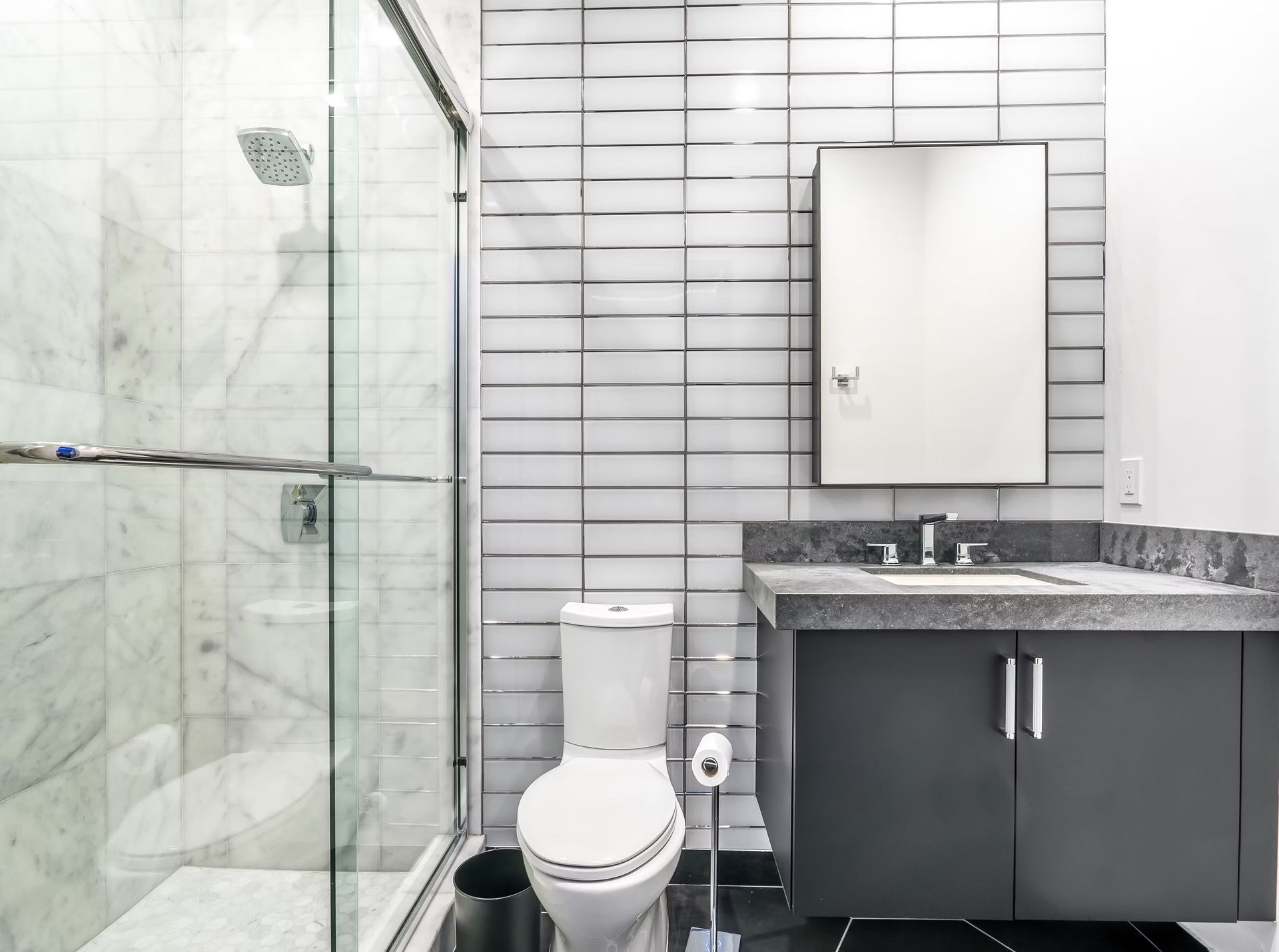 Modern bathroom with glass shower, white toilet, gray vanity, and large mirror