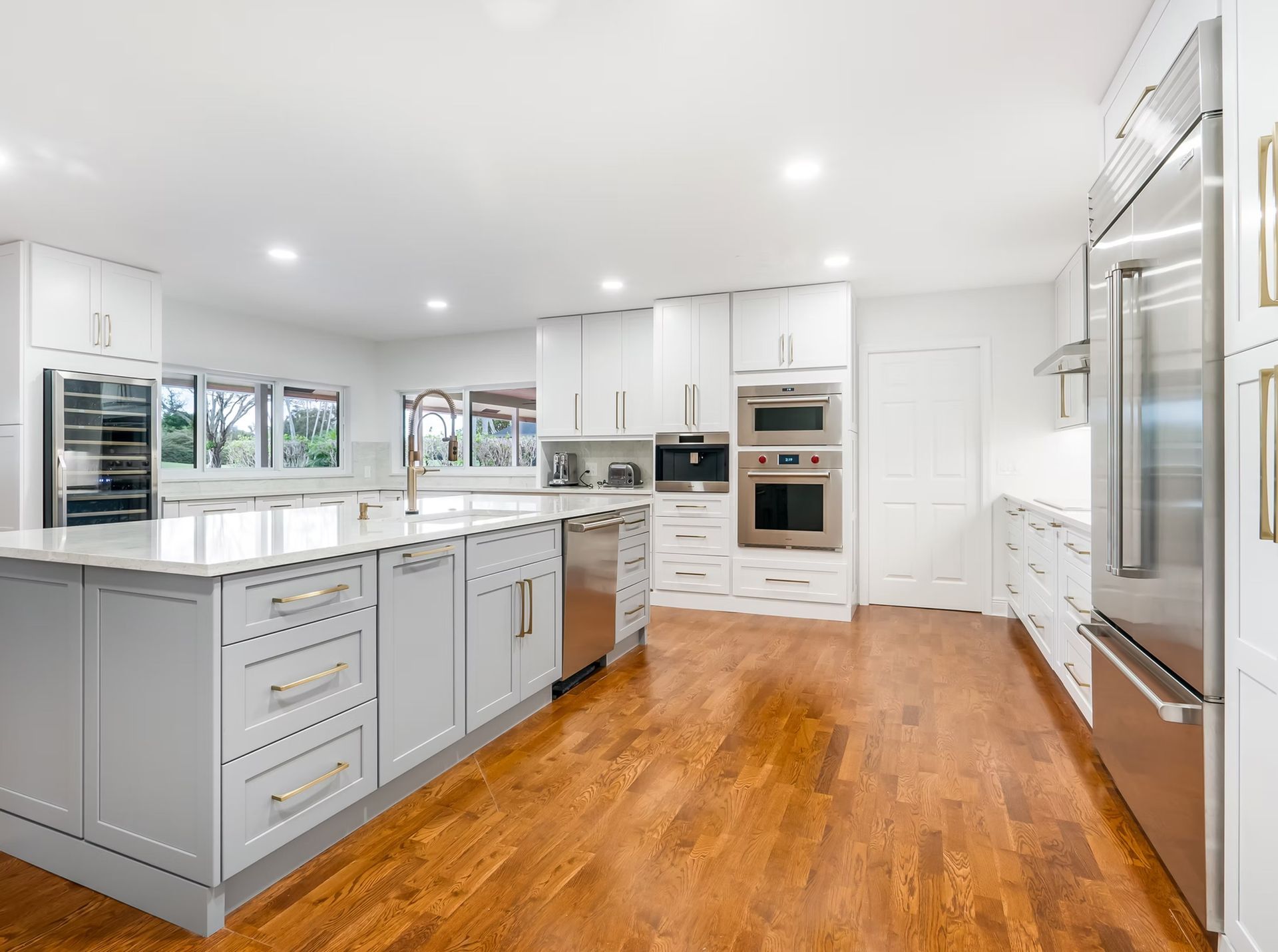Bright modern kitchen with white cabinets, island, stainless appliances, and hardwood floors