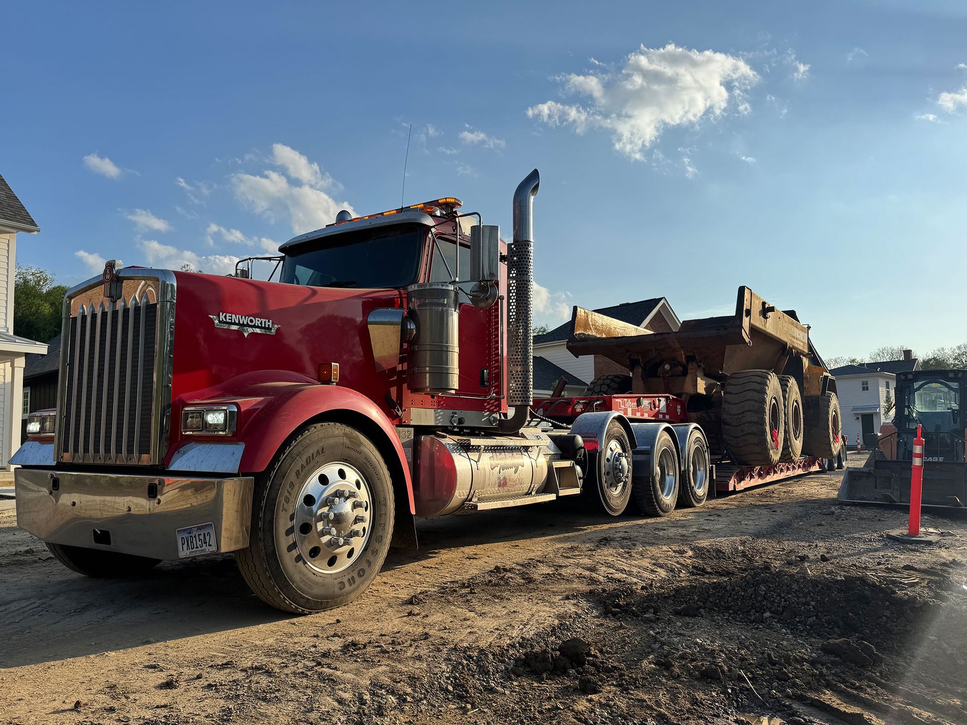 Red dump truck hauling debris on a gravel road under a blue sky