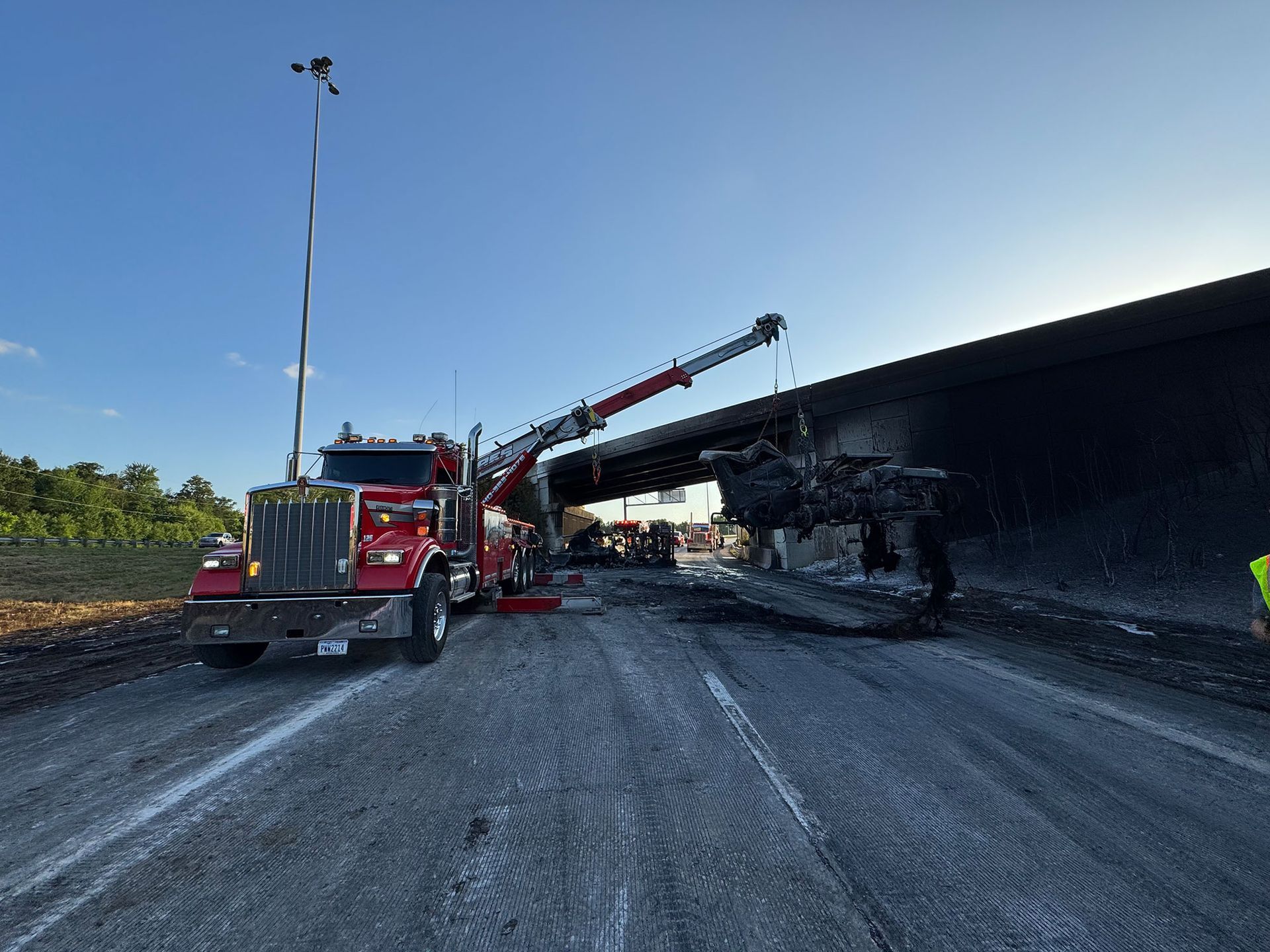Tow truck at a highway bridge collapse site, with debris and an overturned car under the overpass