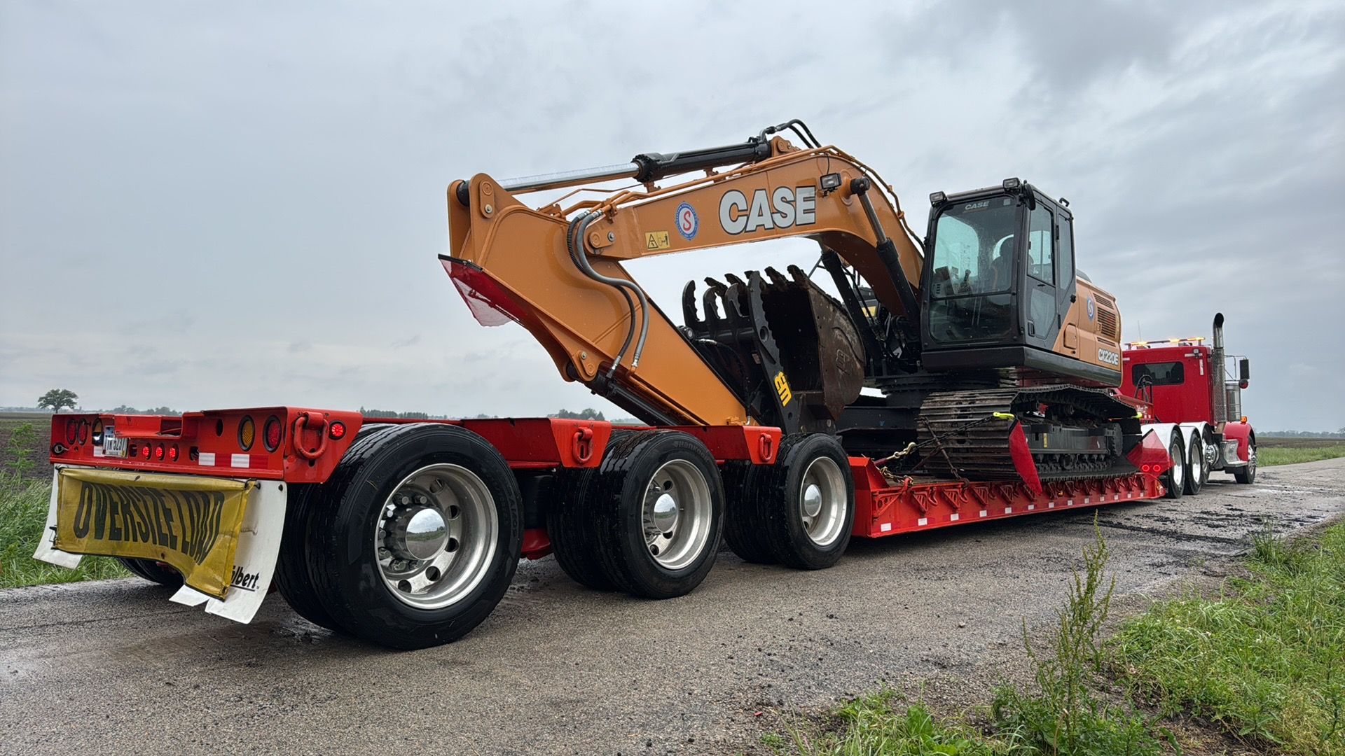 Red Casey road train hauling a large orange excavator on a red lowboy trailer