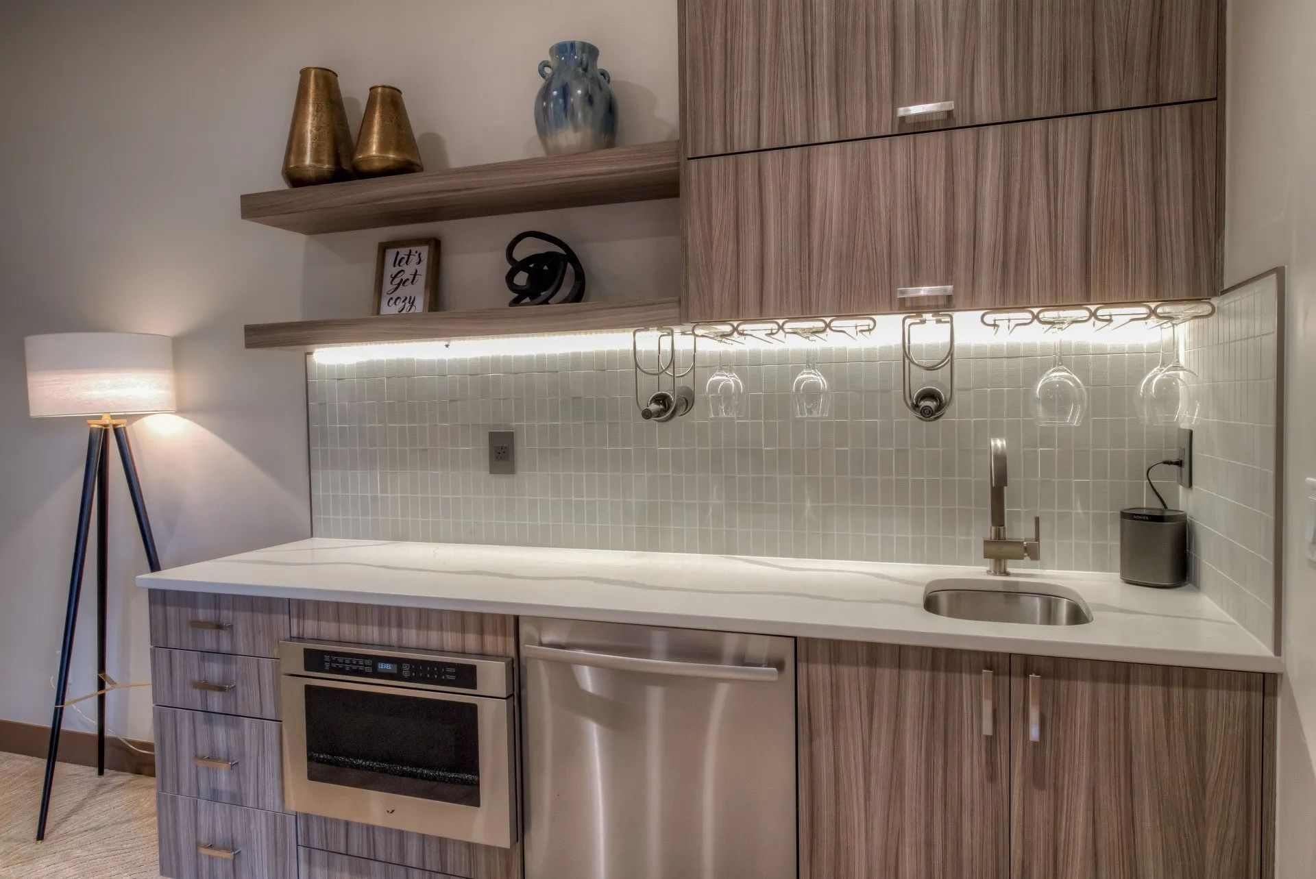 Modern kitchen with wood cabinets, white countertops, stainless appliances, and a floor lamp
