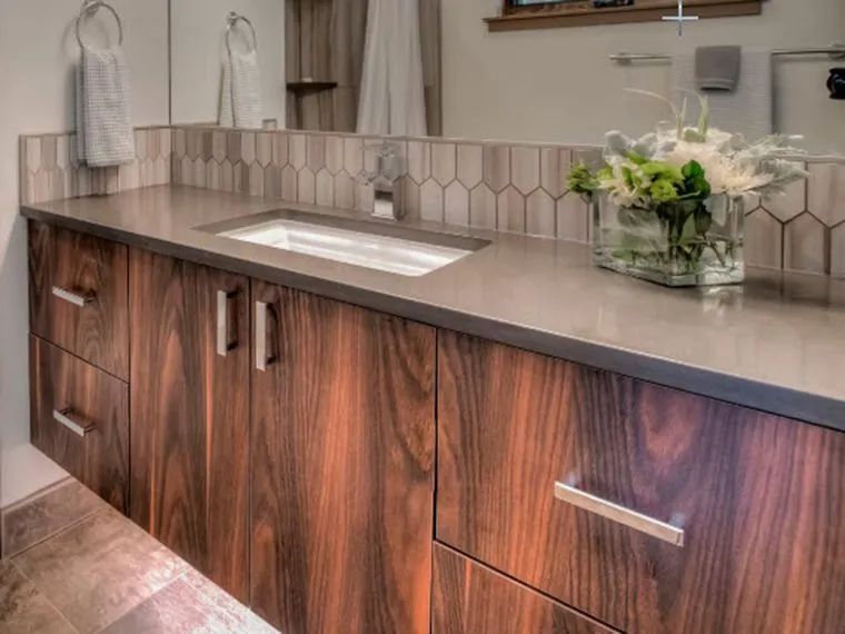 Modern bathroom vanity with wood cabinets, stone countertop, sink, and floral arrangement
