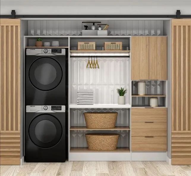 Built-in laundry closet with stacked black washer-dryer, shelves, baskets, and wood cabinetry