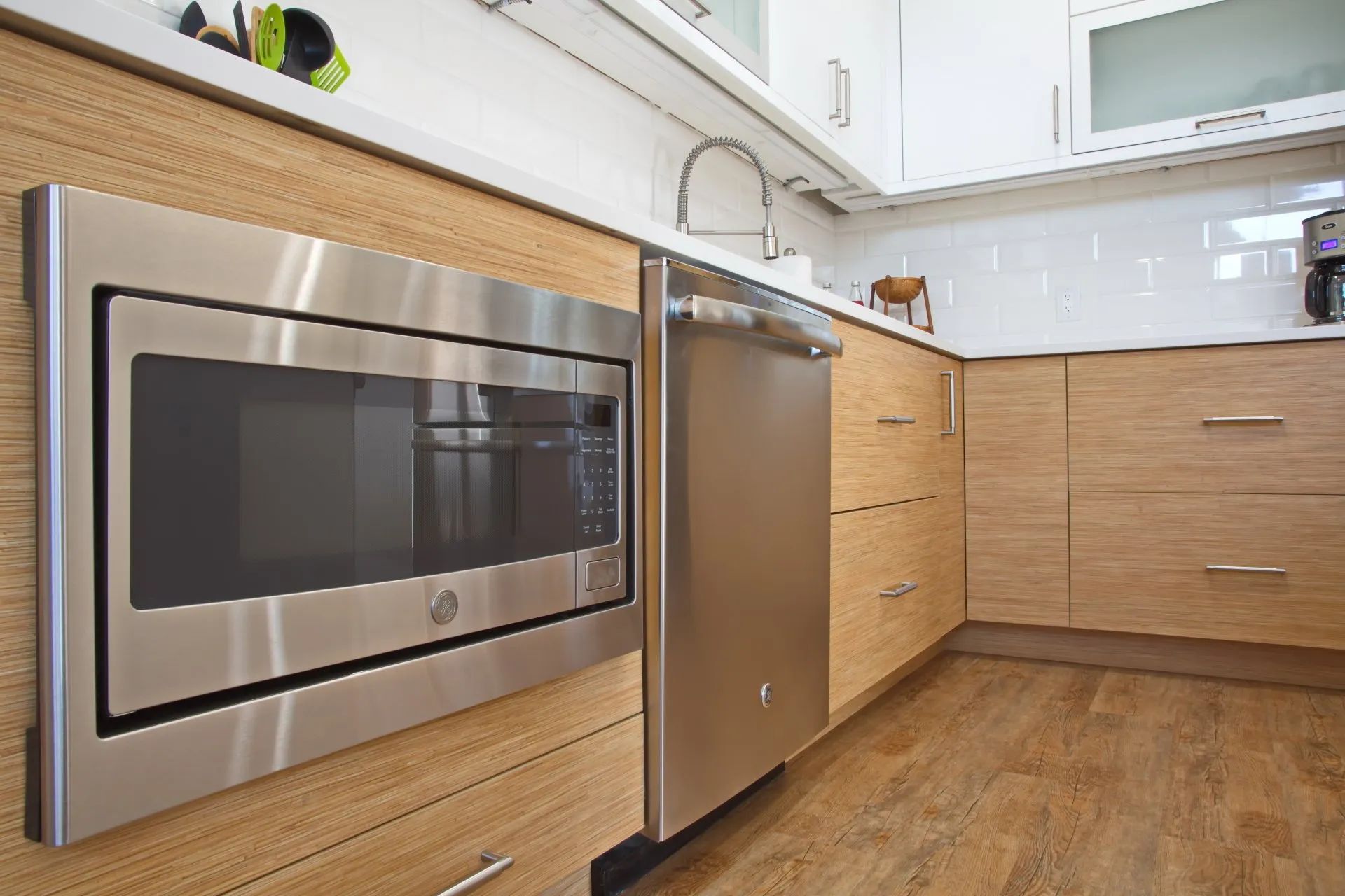 Modern kitchen with stainless steel built-in oven, fridge, wood cabinets, and hardwood floor