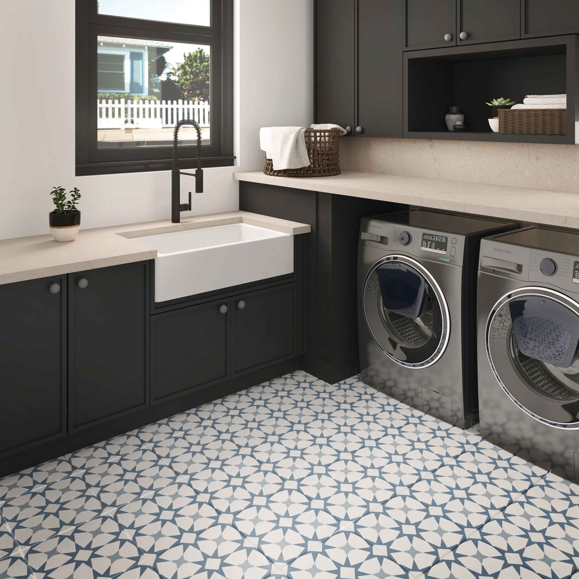 Modern laundry room with black cabinets, white sink, front-loading washer and dryer, and patterned tile floor