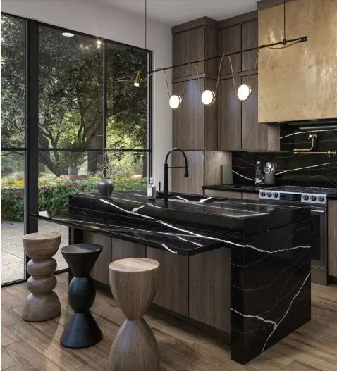 Modern kitchen with black marble island, wood cabinets, pendant lights, and stools by a large window
