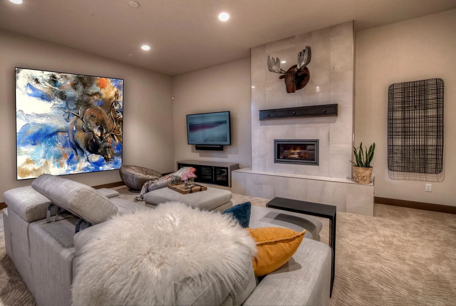 Modern living room with gray sectional, abstract art, fireplace, TV, and beige carpet