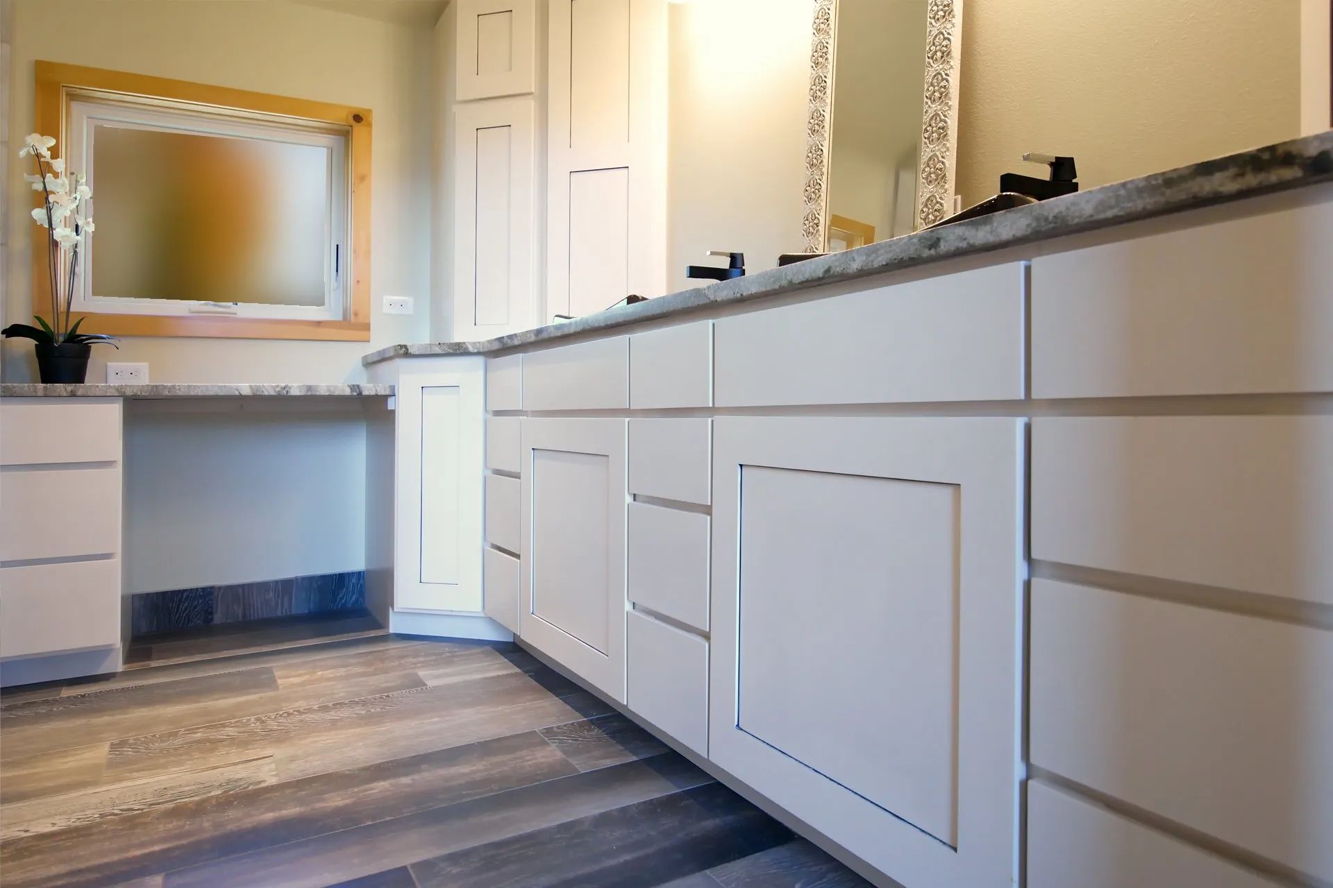 Modern bathroom with white cabinets, dark countertop, and large mirror above a sink.