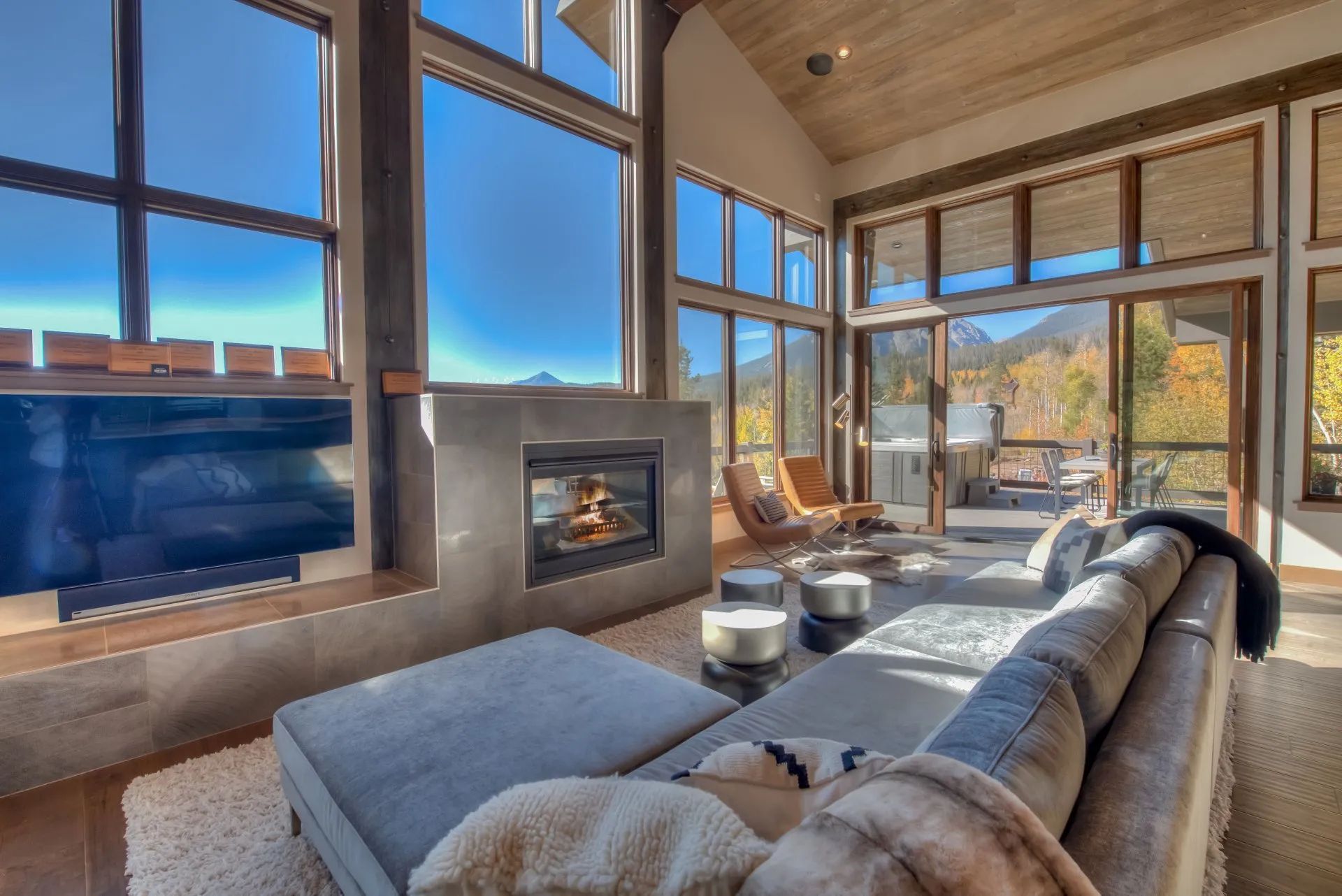 Sunlit modern living room with large windows, a fireplace, and a gray sectional sofa