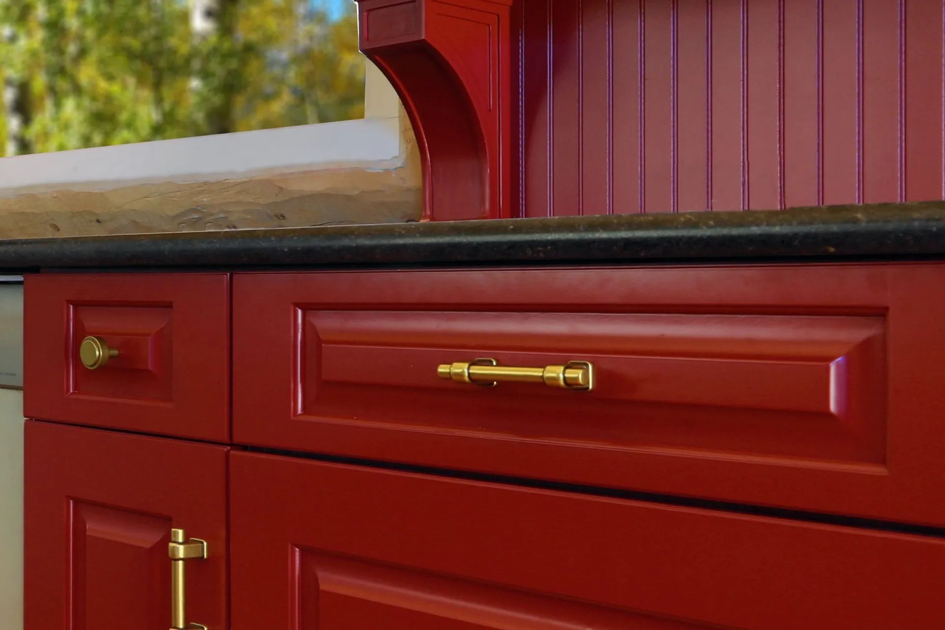Red wooden cabinet with brass handles on a countertop