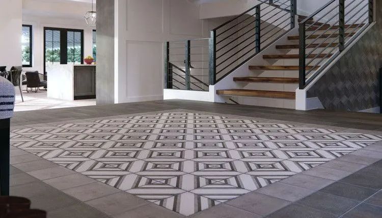 Empty lobby with patterned tile floor, staircase, and a person partly visible at left.