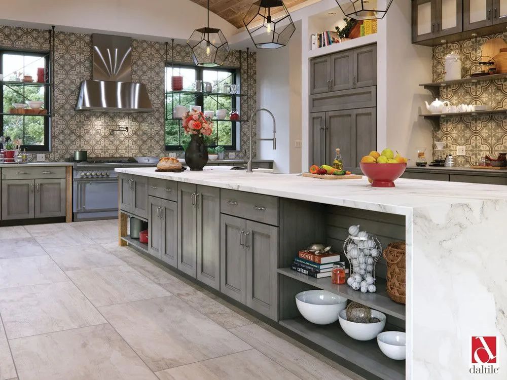 Modern gray kitchen with marble island, tile backsplash, and fruit bowl under pendant lights