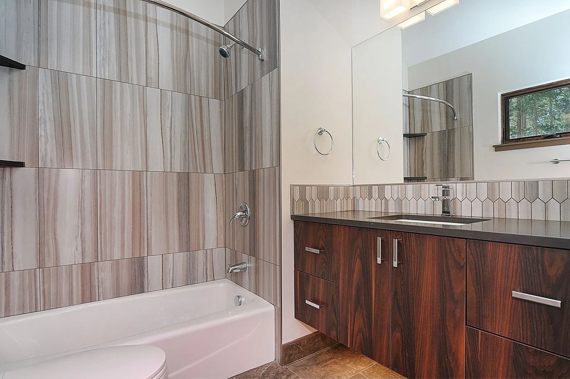 Modern bathroom with a tiled shower, bathtub, double sink vanity, and large mirror