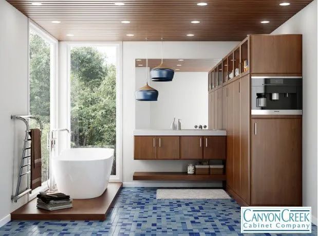 Modern bathroom with freestanding tub, wood cabinetry, blue mosaic floor, and large windows