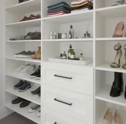 White walk-in closet with shoes, folded clothes, toiletries, and drawers.
