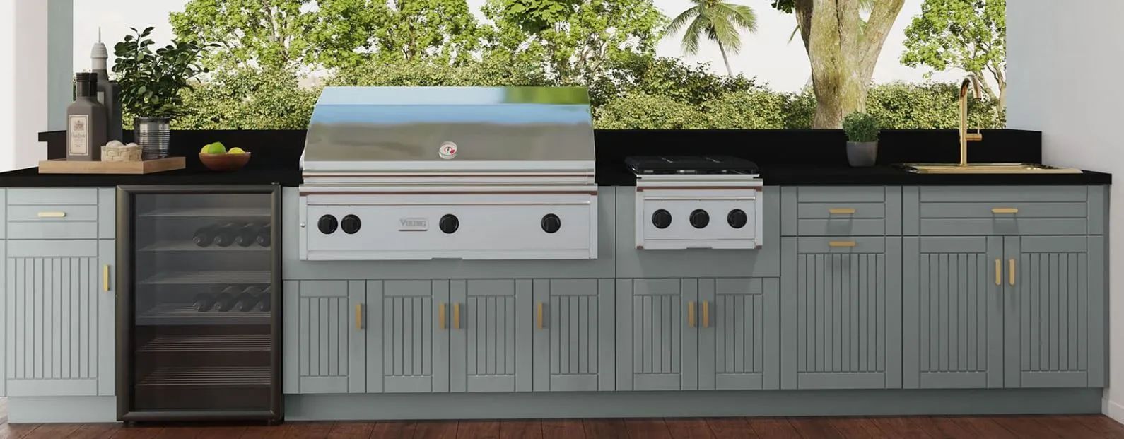 Outdoor kitchen with gray cabinetry, stainless steel grill, beverage fridge, and black countertops under trees