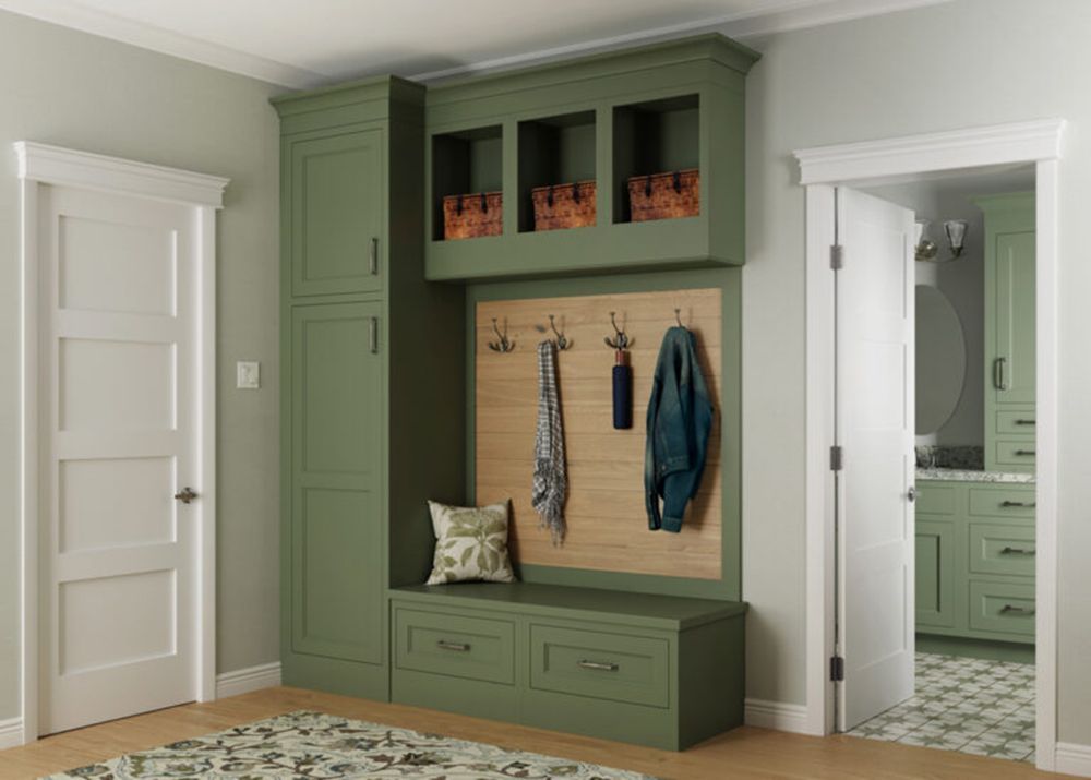 Green built-in mudroom bench with hooks, cabinets, and open cubbies beside white doors.