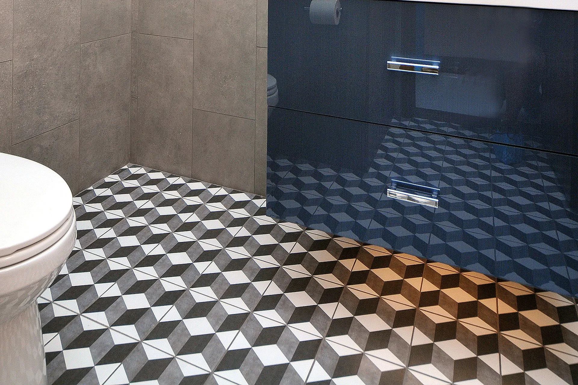 Bathroom with geometric black-and-white tile floor, white toilet, and dark blue cabinet.