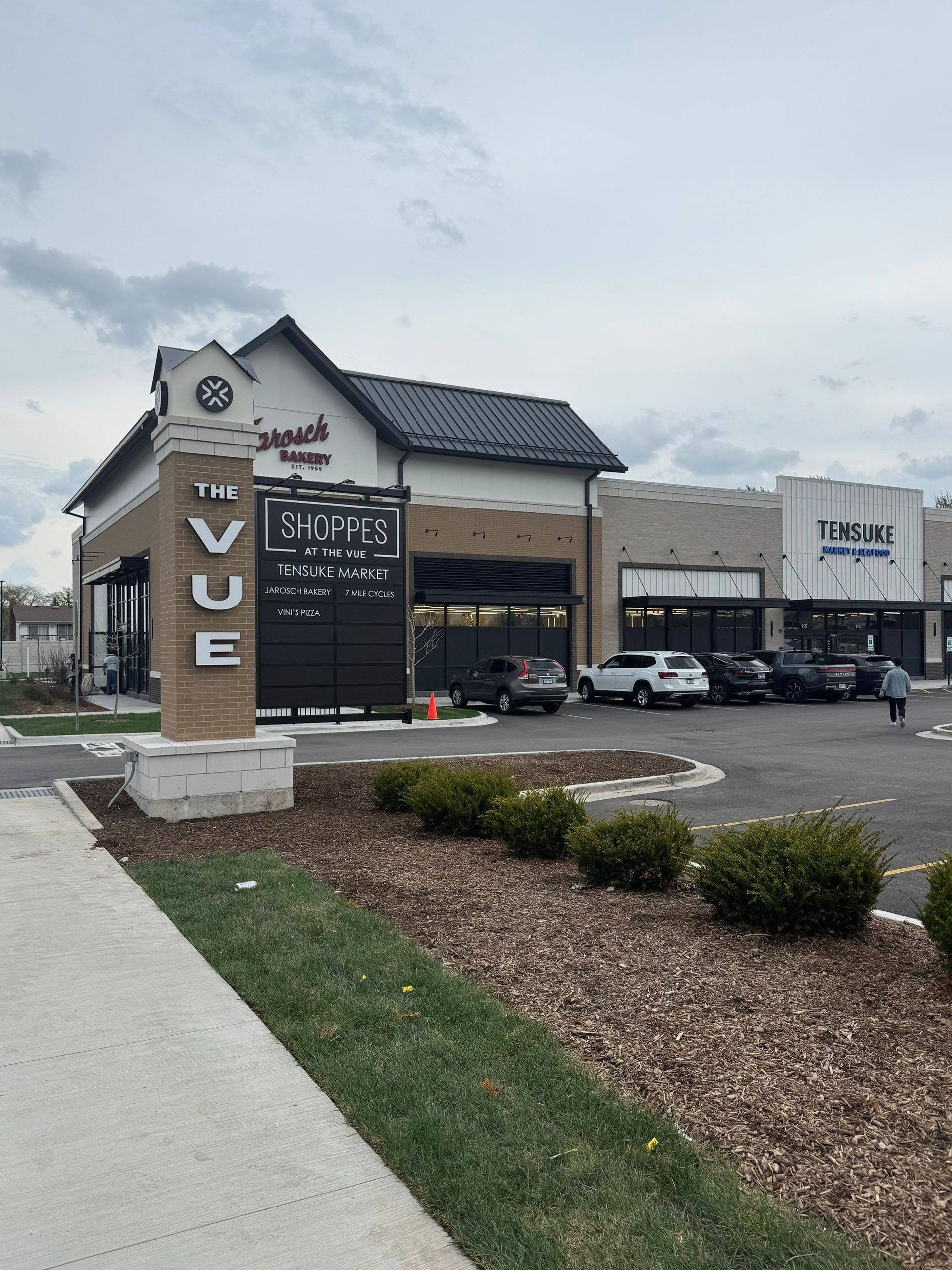 Modern storefront with a black-and-white “Revue” sign and parked cars on an overcast day
