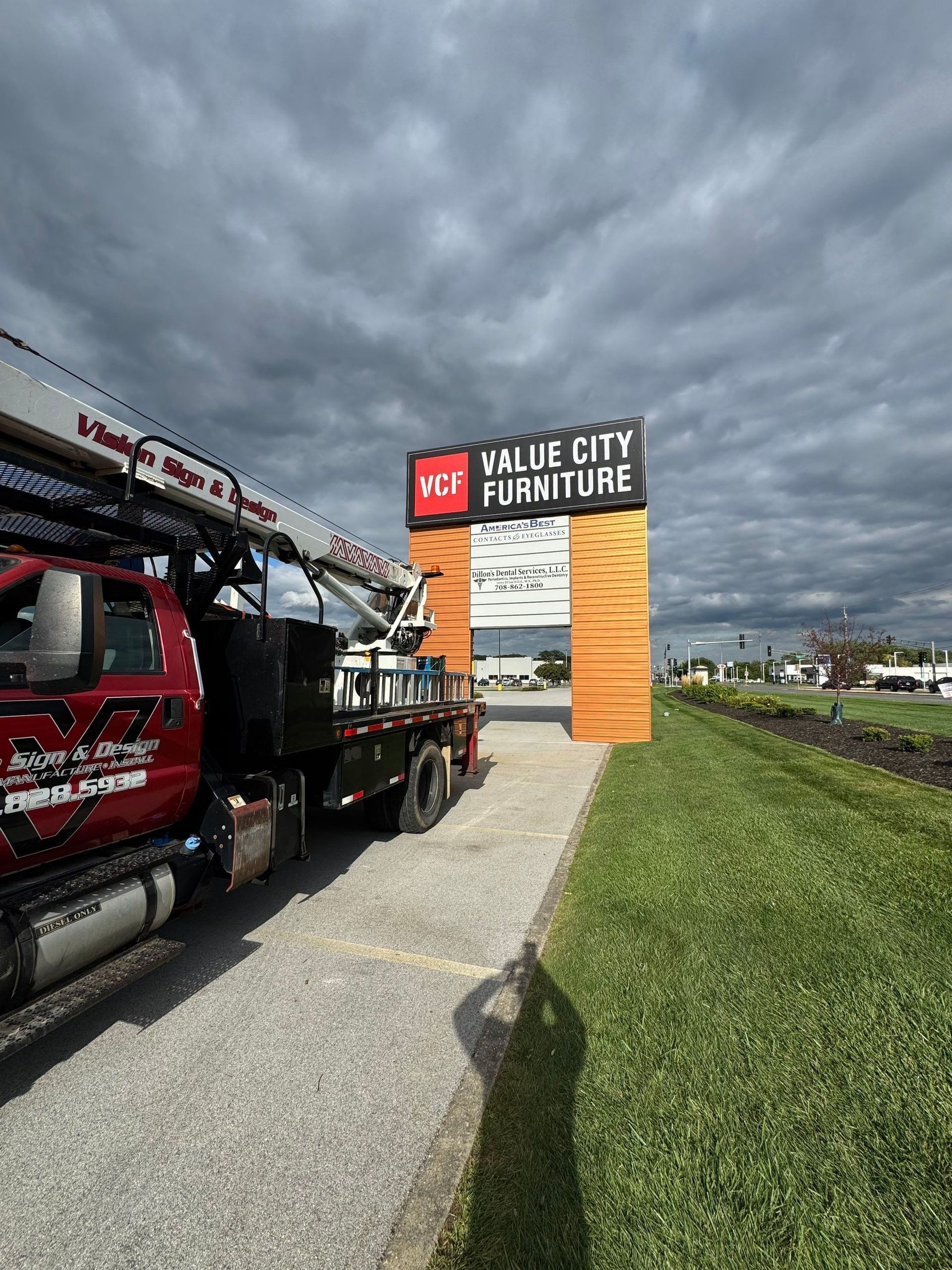 Red tow truck beside a yellow race arch reading “Yallie City Fairgrounds” under cloudy sky