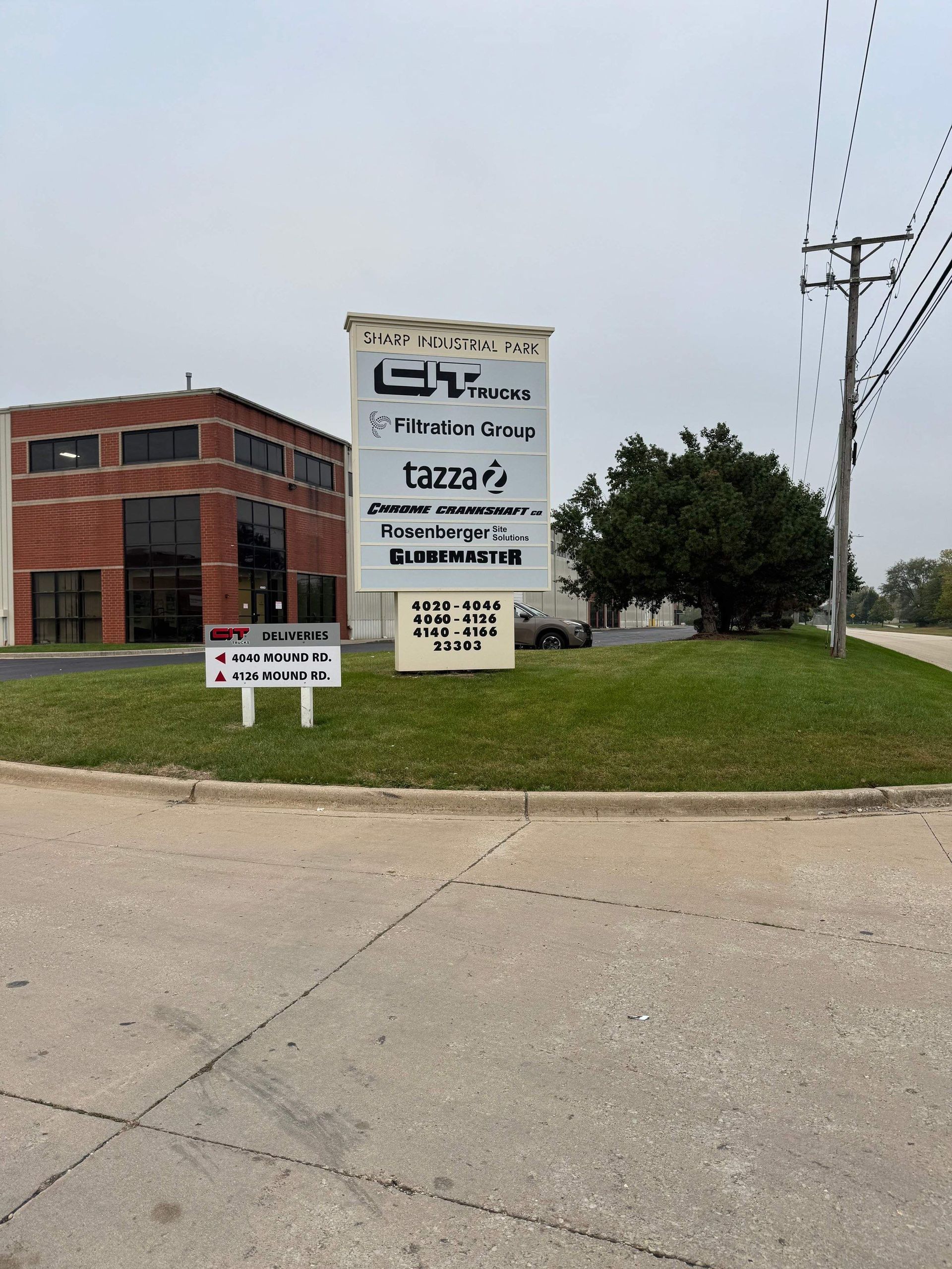 Brick office building with a large roadside business sign on a grassy corner lot.