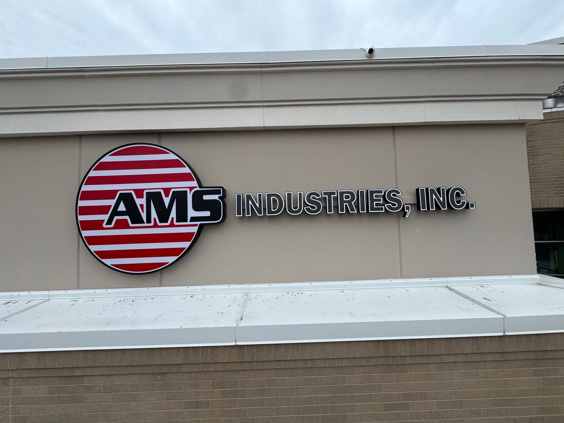 AMS Industries, Inc. logo sign on a beige building exterior