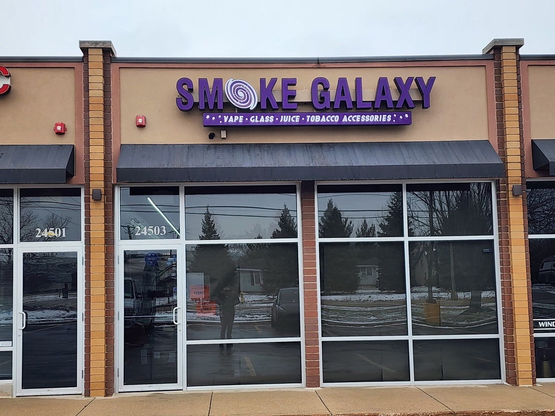 Storefront of Smoke Galaxy with purple sign and large glass windows in a strip mall.