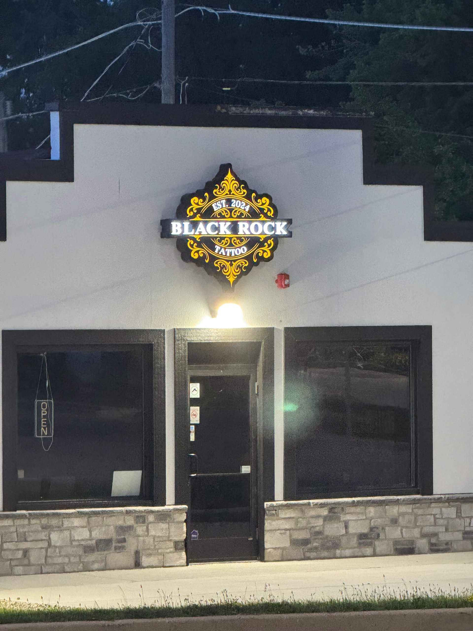 Front view of Black Rock bar at night with illuminated sign and stone facade.