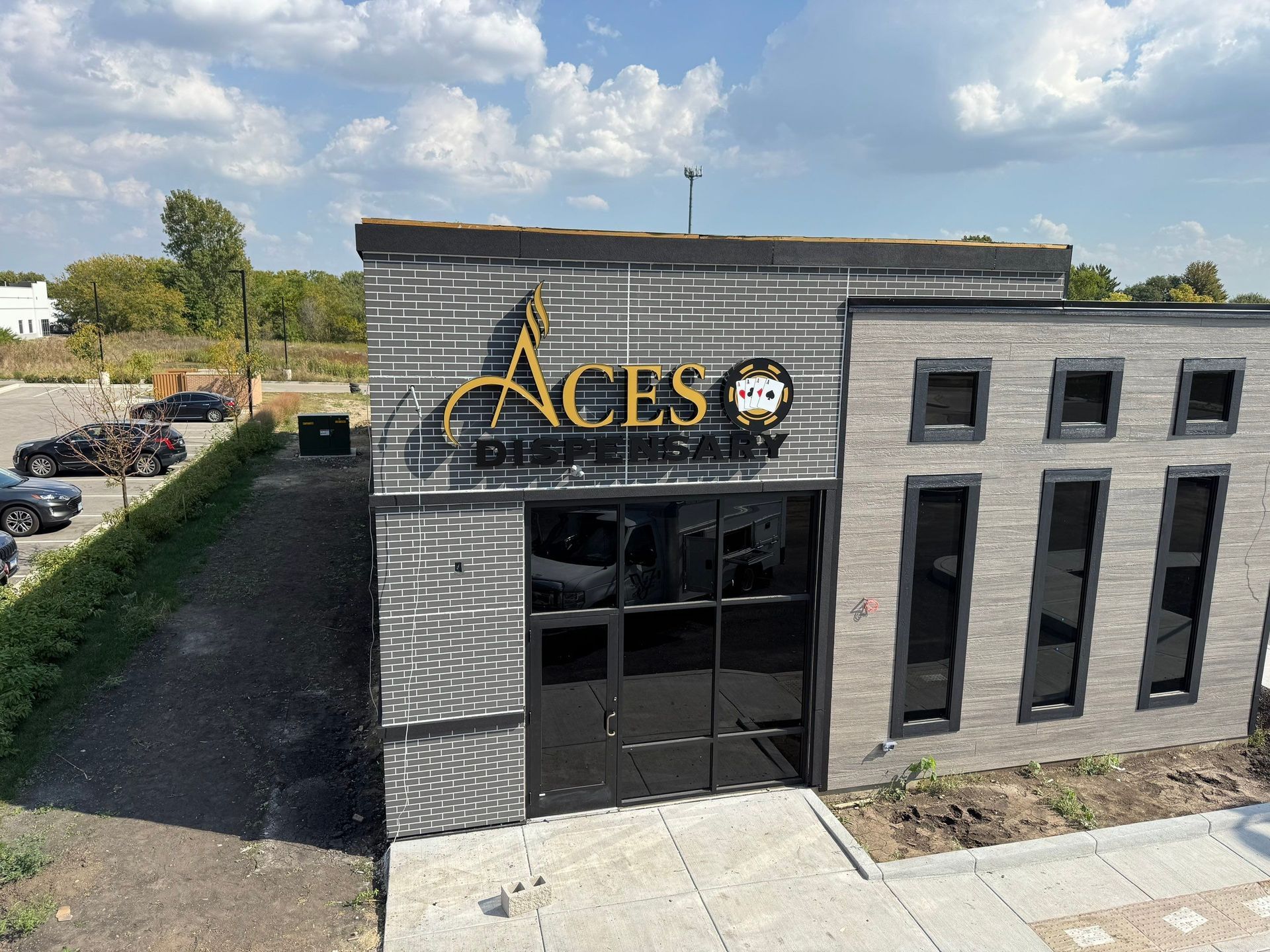 Aces building exterior with gray brick facade and black entrance doors under a blue sky