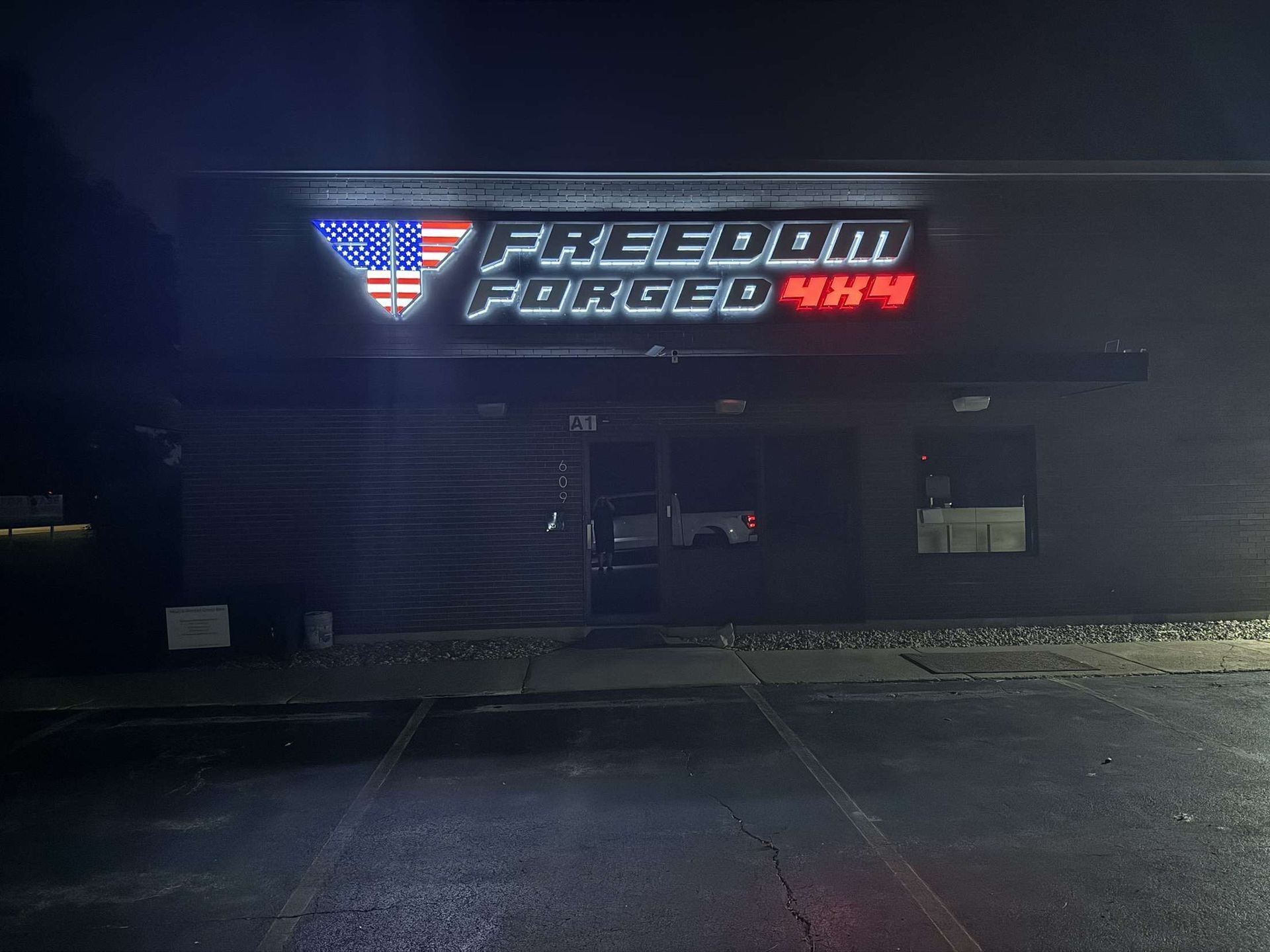 Dark storefront sign reading “Freedom Tobacco” glowing above a closed building at night